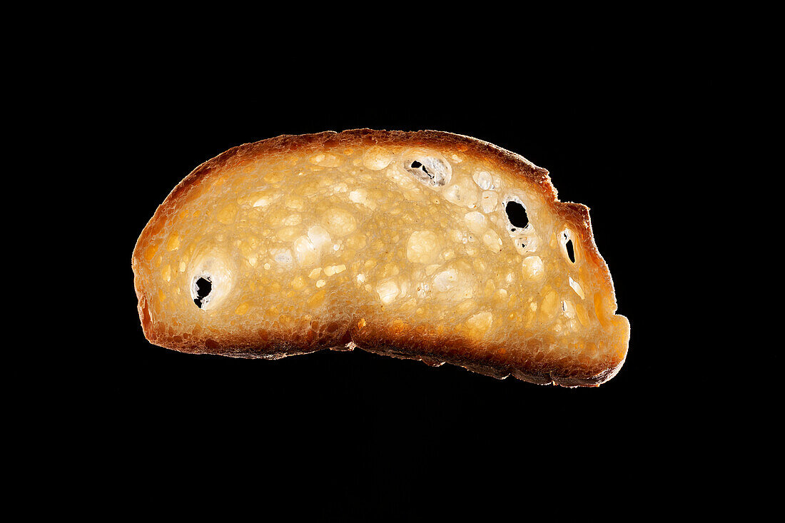 Slice of freshly baked bread against black background