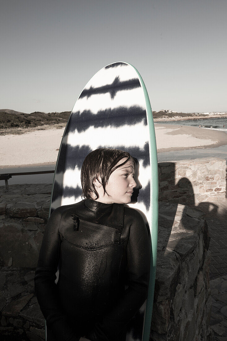 Portrait of boy (10-11) posing against surfboard at Onrus Beach