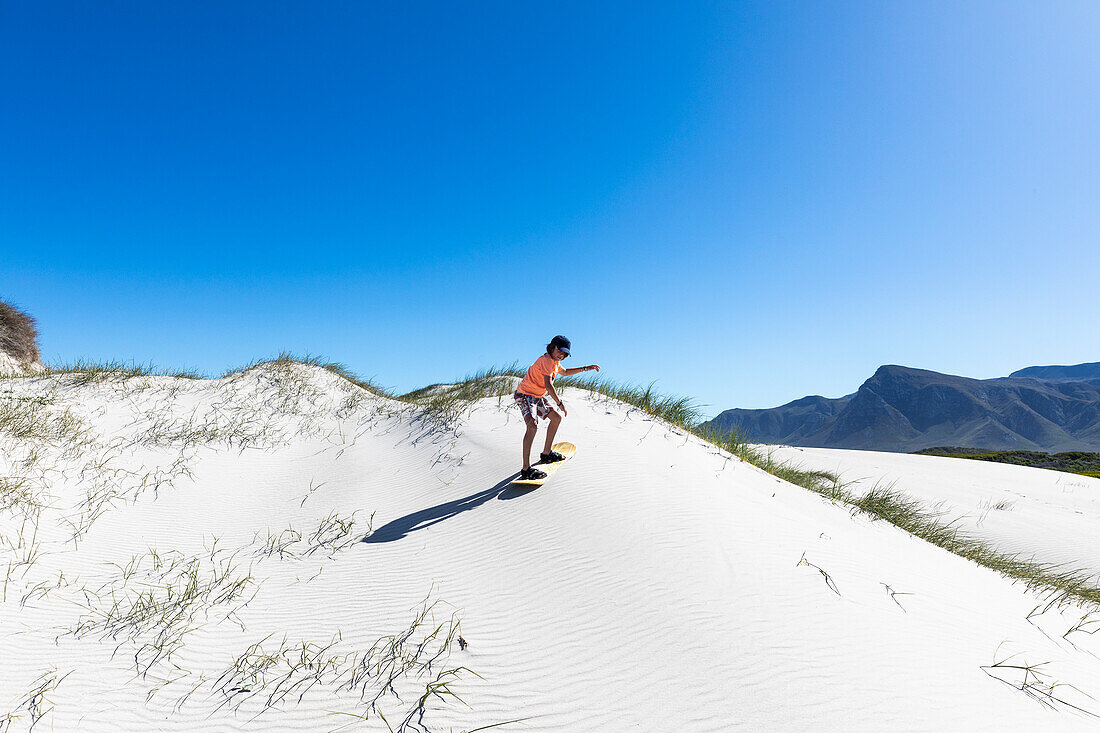 Boy (10-11) sand boarding in Walker Bay Nature Reserve