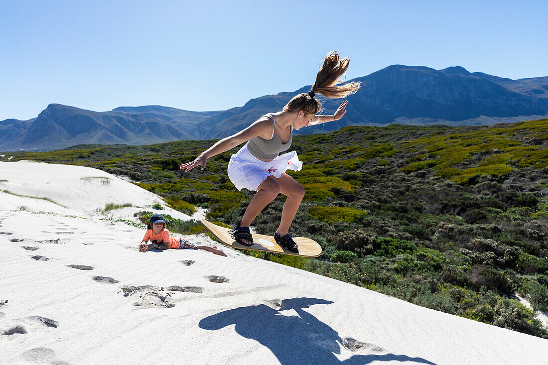 Südafrika, Mädchen (16-17) und Junge (10-11) beim Sandboarding im Walker Bay Naturreservat