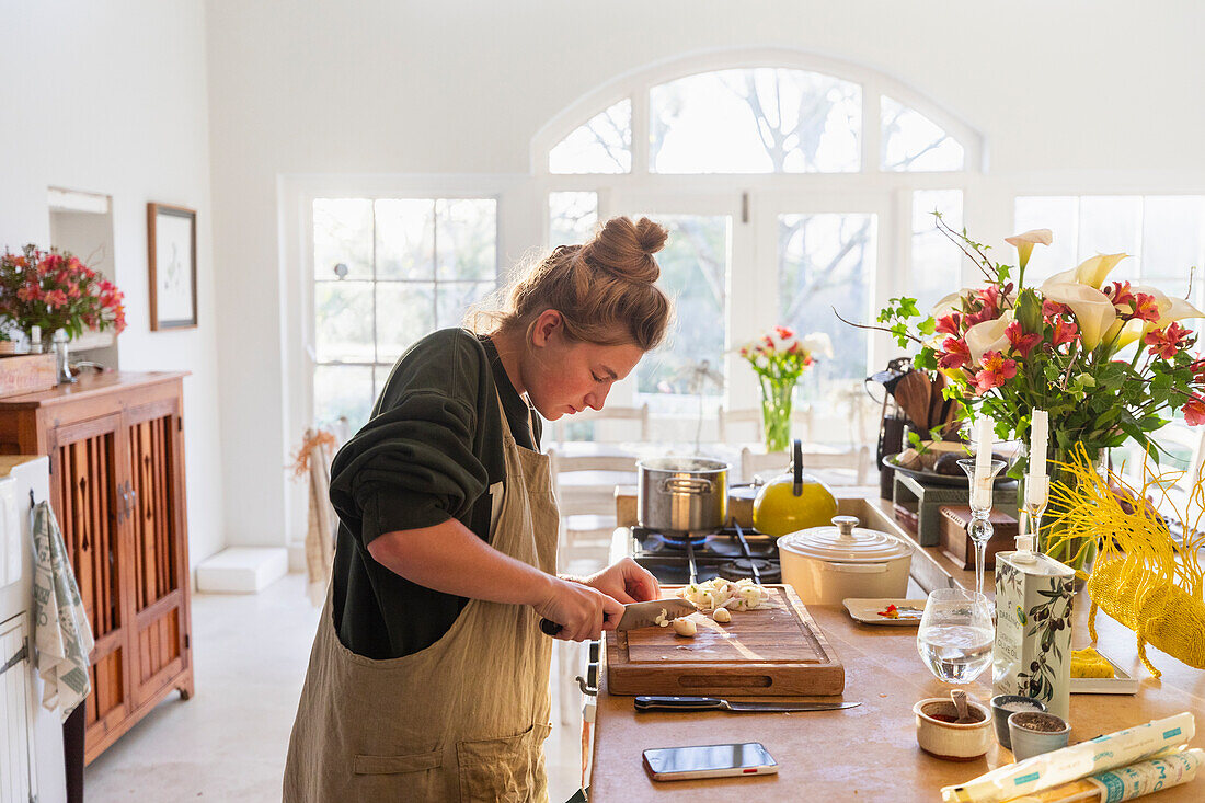 Teenage girl (16-17) preparing meal in kitchen