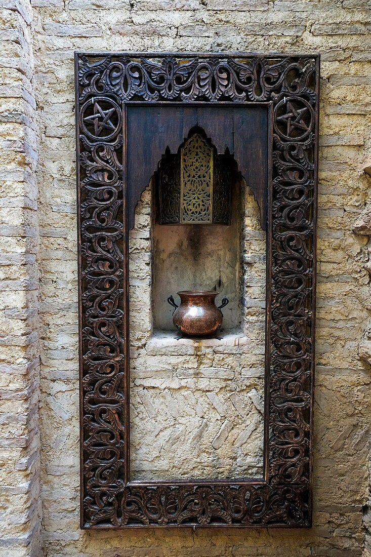 Fes, Morocco. Old copper pot sits on a ledge with a carved wooden frame.