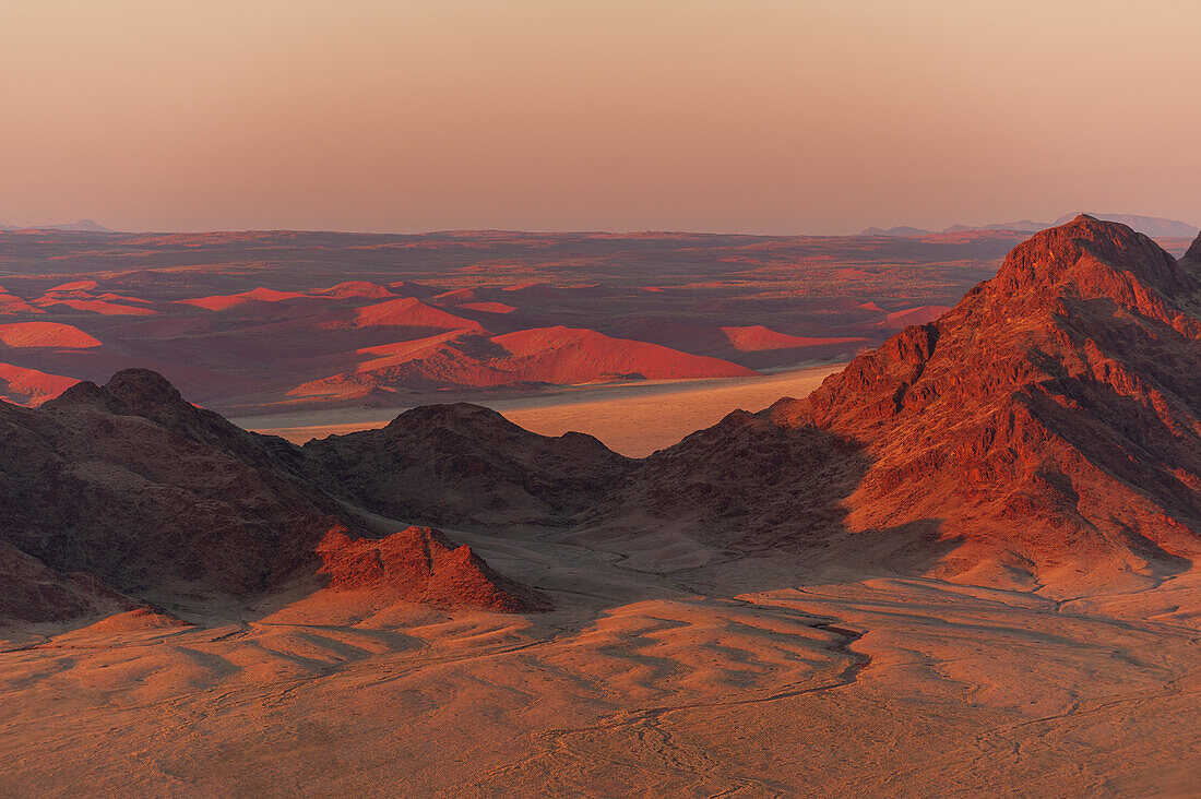 Licht beleuchtet die Naukluft-Berge und die Namib-Wüste bei Sonnenaufgang. Namib-Naukluft-Park, Namibia.