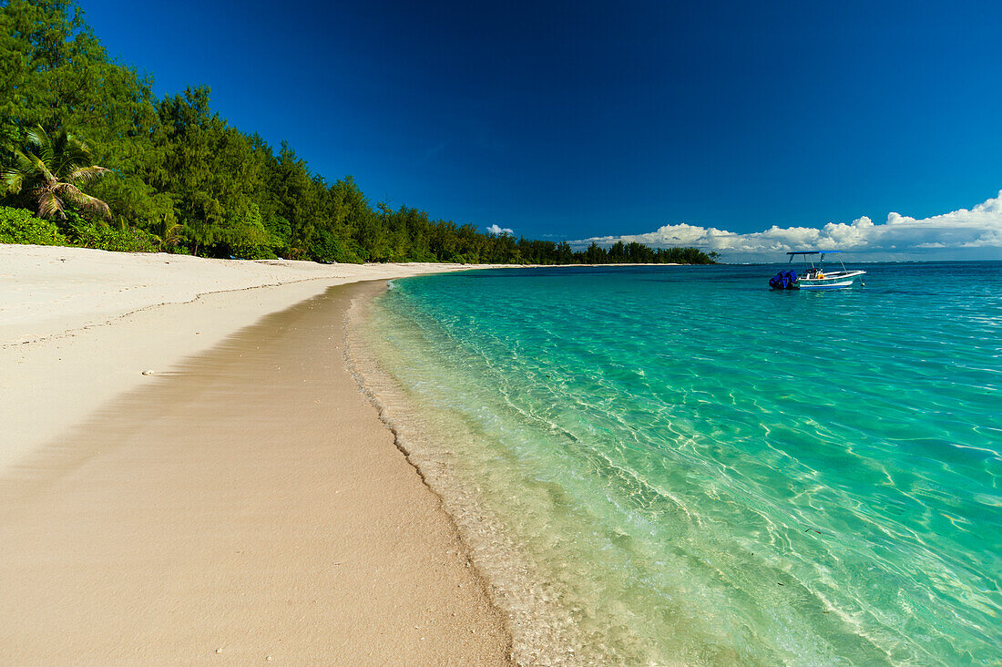 A boat anchored off the shore of a pristine tropical beach. Denis Island, Seychelles.