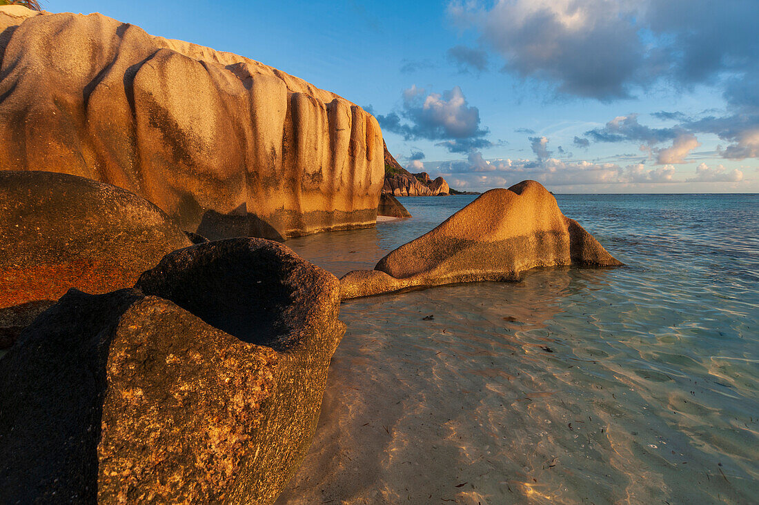 Rock formations on a tropical island beach in warm sunlight at sunset. Anse Source d 'Argent Beach, La Digue Island, Seychelles.