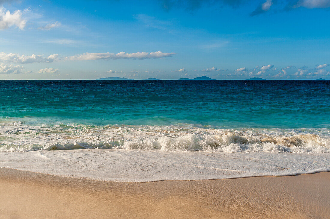 Die Brandung des Indischen Ozeans brandet an einen tropischen Sandstrand. Strand Anse Macquereau, Insel Fregate, Seychellen.