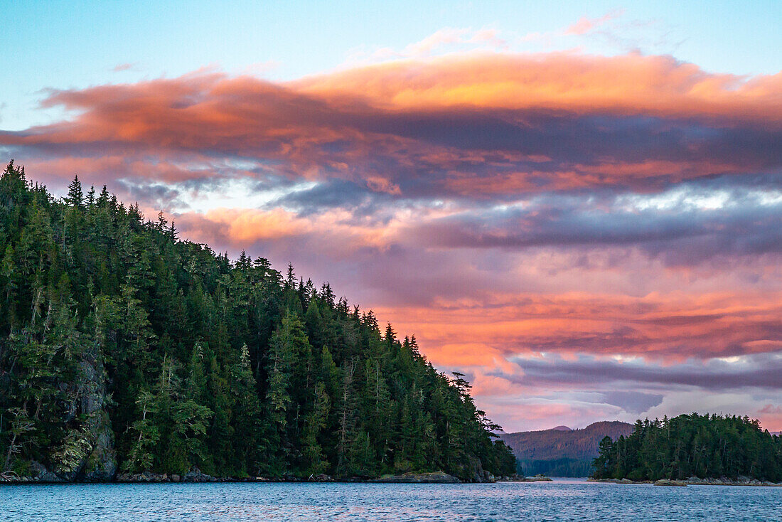 Kanada, Britisch-Kolumbien, Inside Passage. Sonnenaufgang über dem Meer und bewaldeten Bergen.