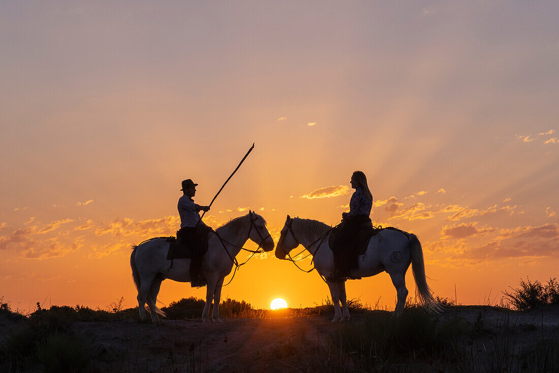 Saintes-Maries-de-la-Mer, Bouches-du-Rhone, Provence-Alpes-Cote d'Azur, France. Man and a woman on horseback at sunrise. (Editorial Use Only)