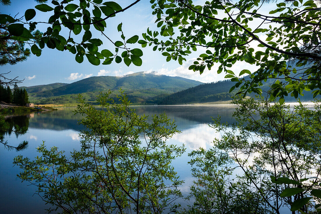 USA, Colorado. Pearl Lake and mountains framed through tree branches.