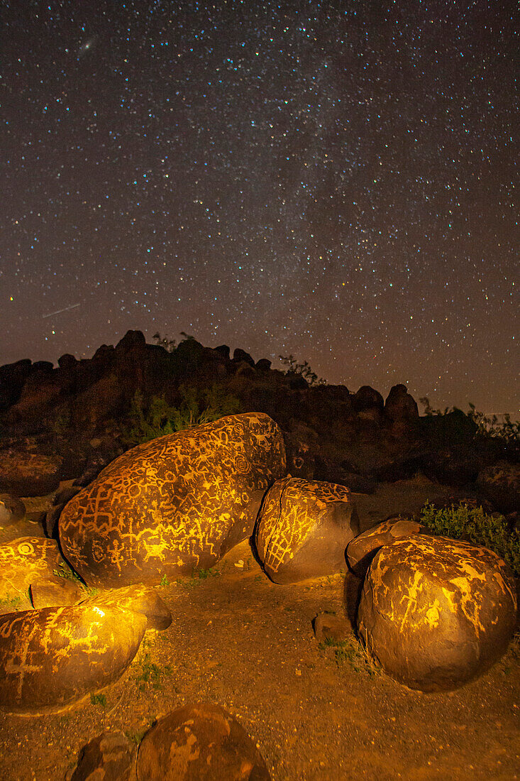 USA, Arizona, Painted Rock Petroglyph Site. Beleuchtete Felsen-Petroglyphen und Sternenhimmel.