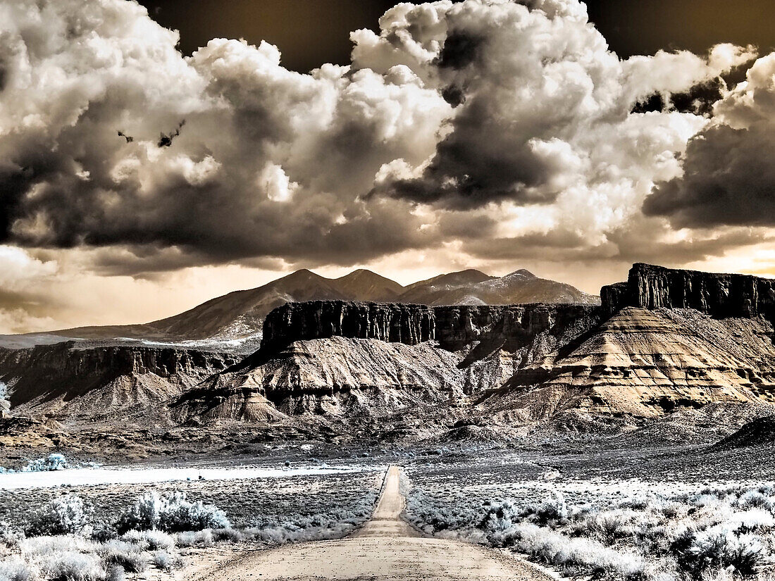 USA, Utah. Infrarot der Straße, die zum Fisher Tower führt, und große Wolken