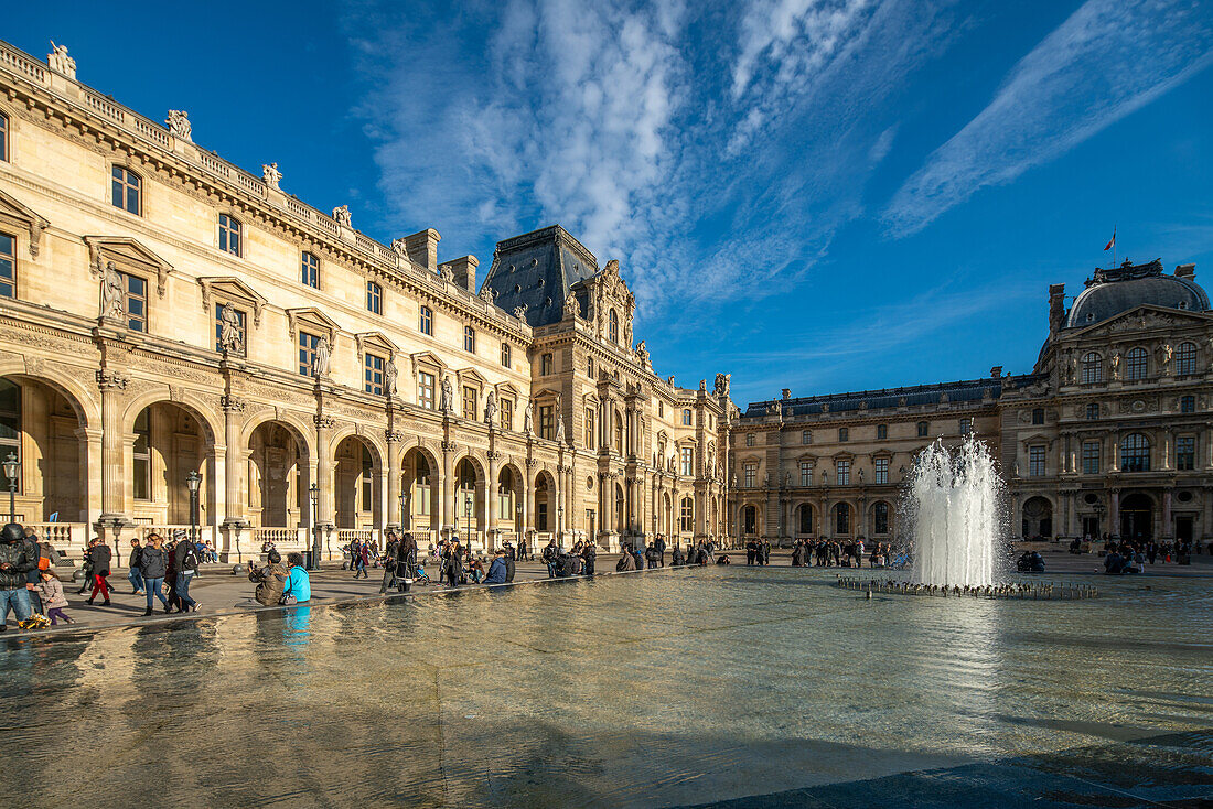 Visitors walking near the Palais Royal under a clear blue sky.