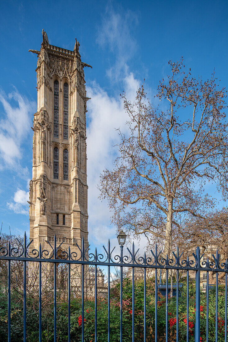 Tour Saint Jacques stands tall against a blue sky, behind ornate fencing.