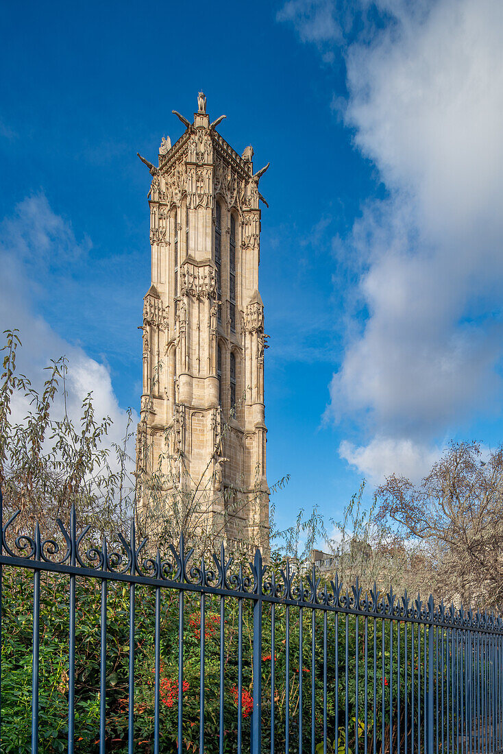 Tour Saint Jacques stands tall against a blue sky, behind ornate fencing.