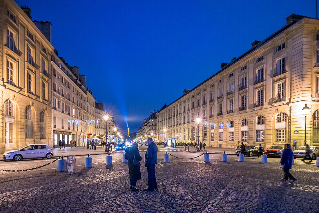 Eiffel Towers light beam visible from Pantheon square in the evening.