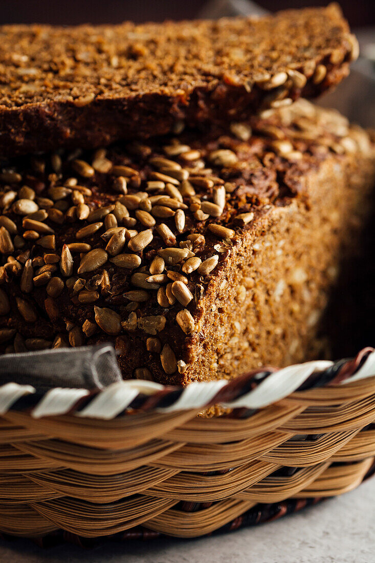 Nahaufnahme von leckerem geschnittenem Brot mit brauner Kruste und knusprigen Sonnenblumenkernen in einem Weidenkorb