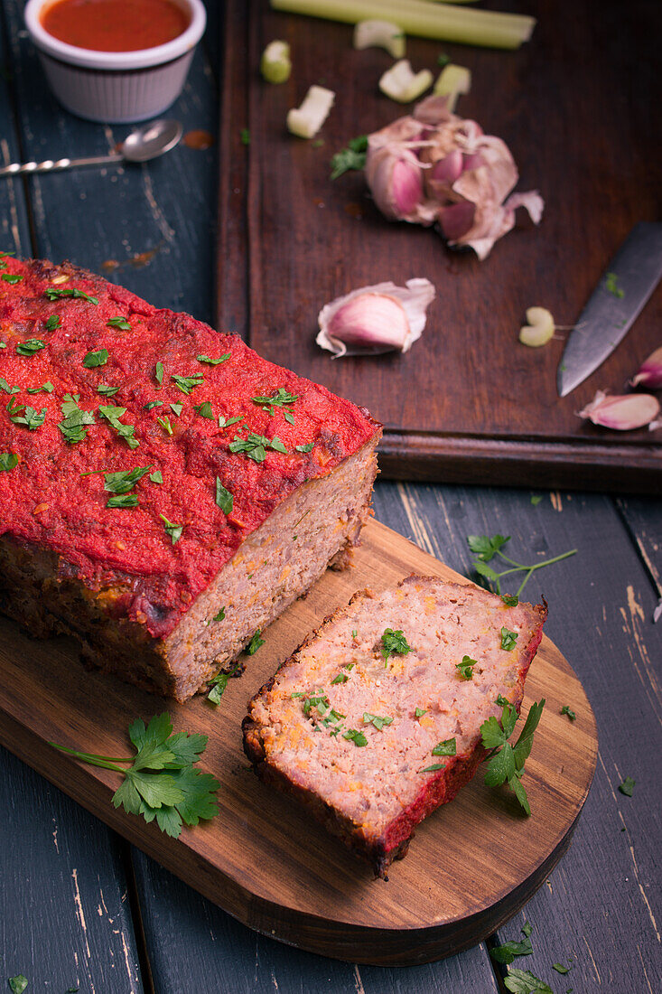 Von oben köstlicher hausgemachter Hackbraten mit Karotten und frischer grüner Petersilie auf einem hölzernen Schneidebrett auf dem Tisch