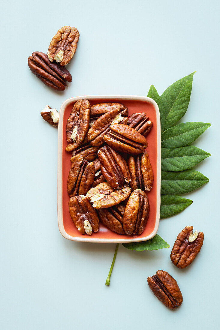 From above shelled Pecan nuts in a bowl against blue background