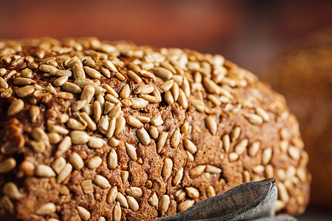 Leckeres Vollkornbrot auf Schneidebrett auf Tisch