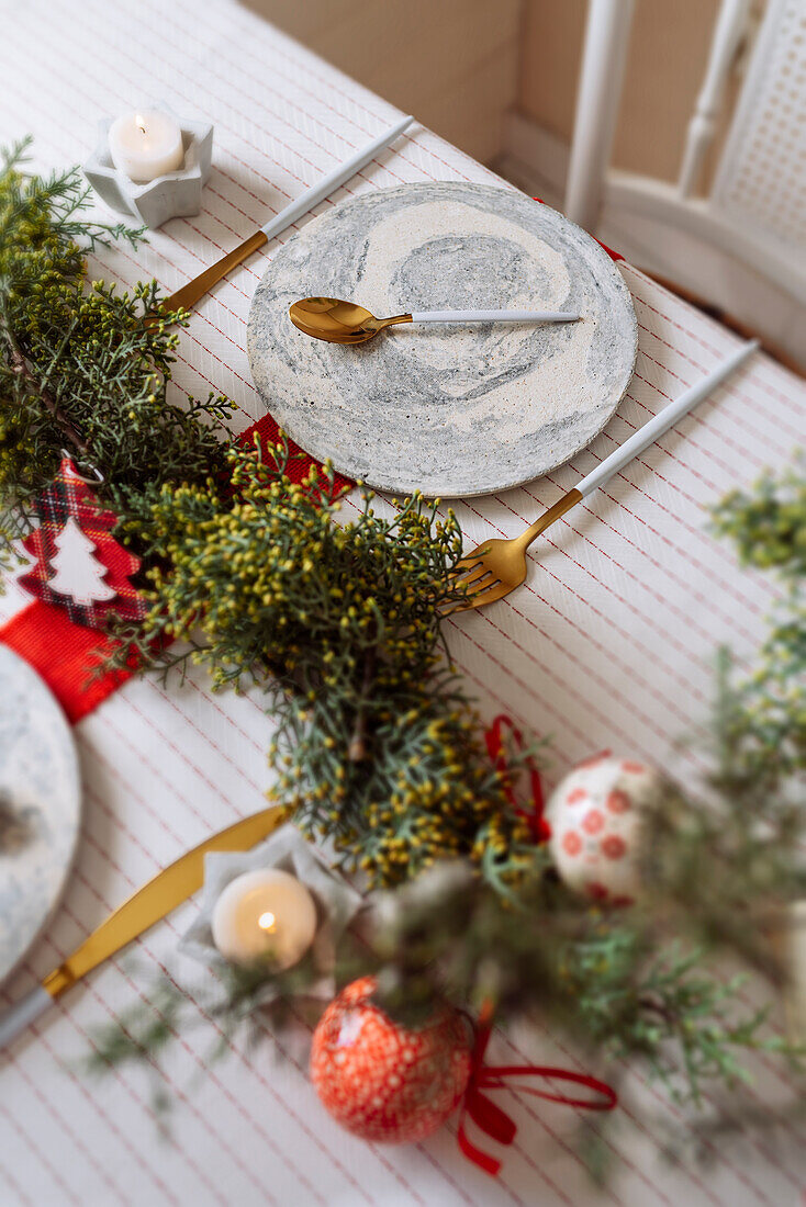 Von oben auf einen weihnachtlich gedeckten Tisch mit Kranzdekoration, rot und weiß, mit goldenem Besteck und Kerzen