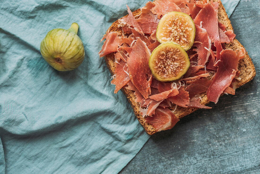 Köstlicher Toast mit Iberico-Schinken, Käse und frischen Feigen auf dem blauen Tischtuch, Köstliche Vorspeise, ideal als Aperitif. Gesundes Essen