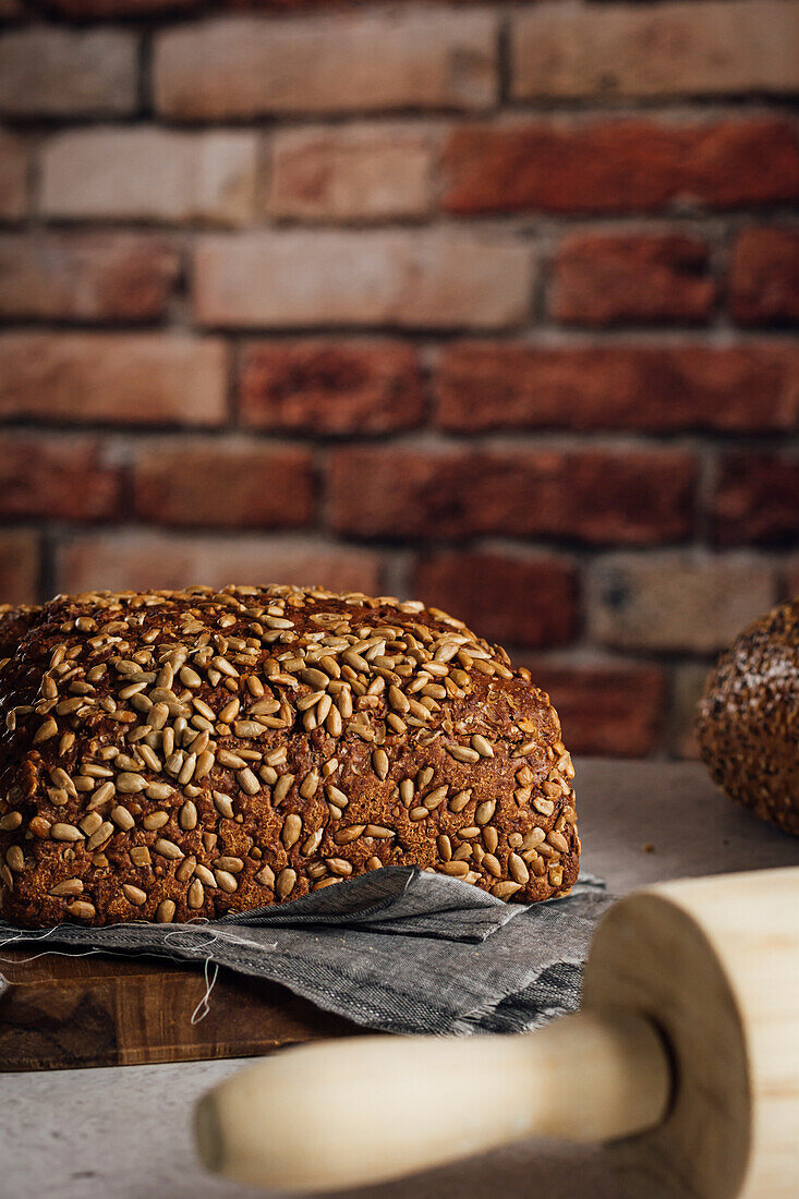 Leckeres Vollkornbrot auf Schneidebrett auf Tisch