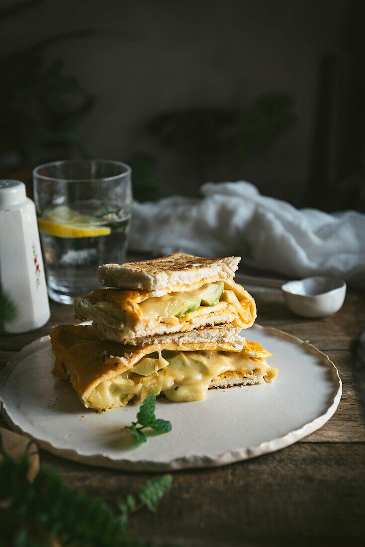 Avocado, Käse, Omelett-Sandwich auf Keramikteller auf Holztisch serviert