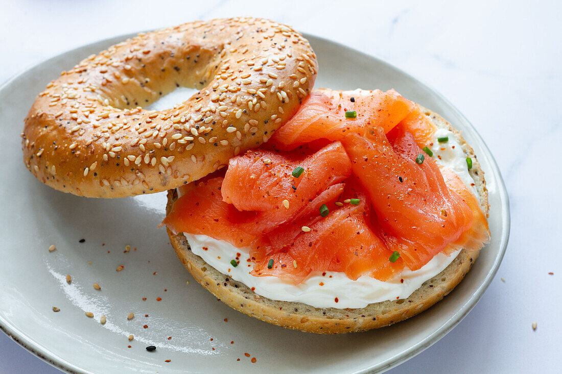 Von oben frischer Bagel mit Käse und Lachs auf einem Teller, serviert auf einem Tisch in einer hellen Küche