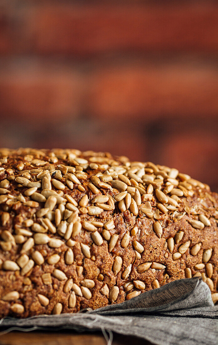 Leckeres Vollkornbrot auf Schneidebrett auf Tisch