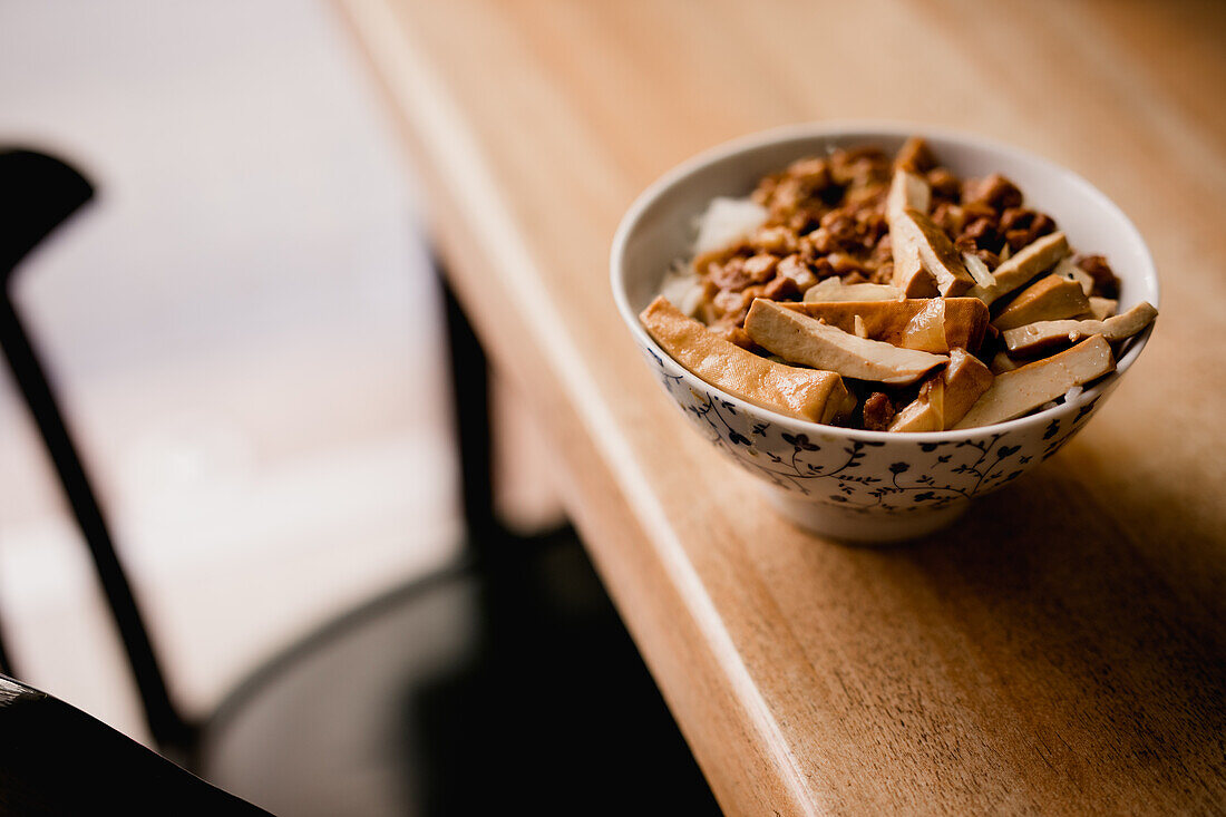 Keramikschüssel mit leckerem Lu Rou Fan-Gericht mit Tofu auf einem Tisch in einem Cafe