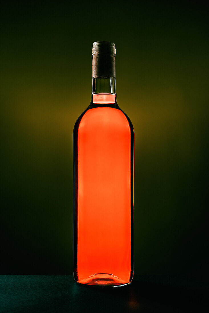 Flasche mit aromatischem Tisch-Rotwein im Studio auf dunklem Hintergrund