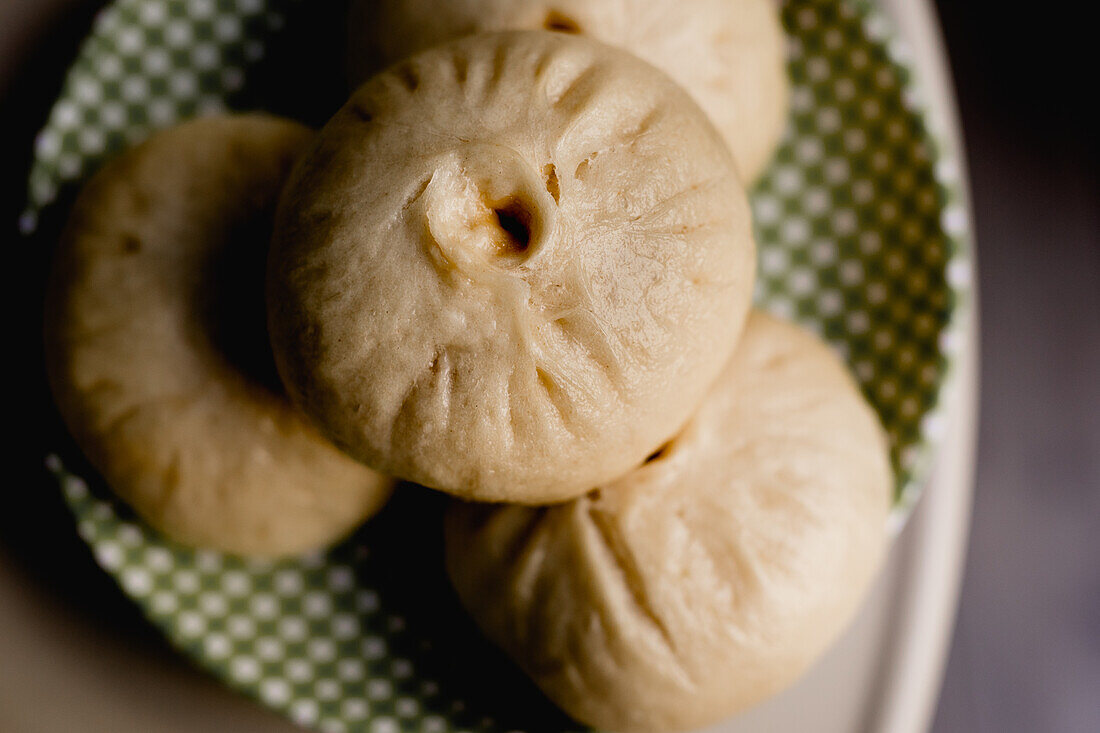 Von oben appetitlich gedämpfte Baozi-Brötchenportion auf kariertem Teller