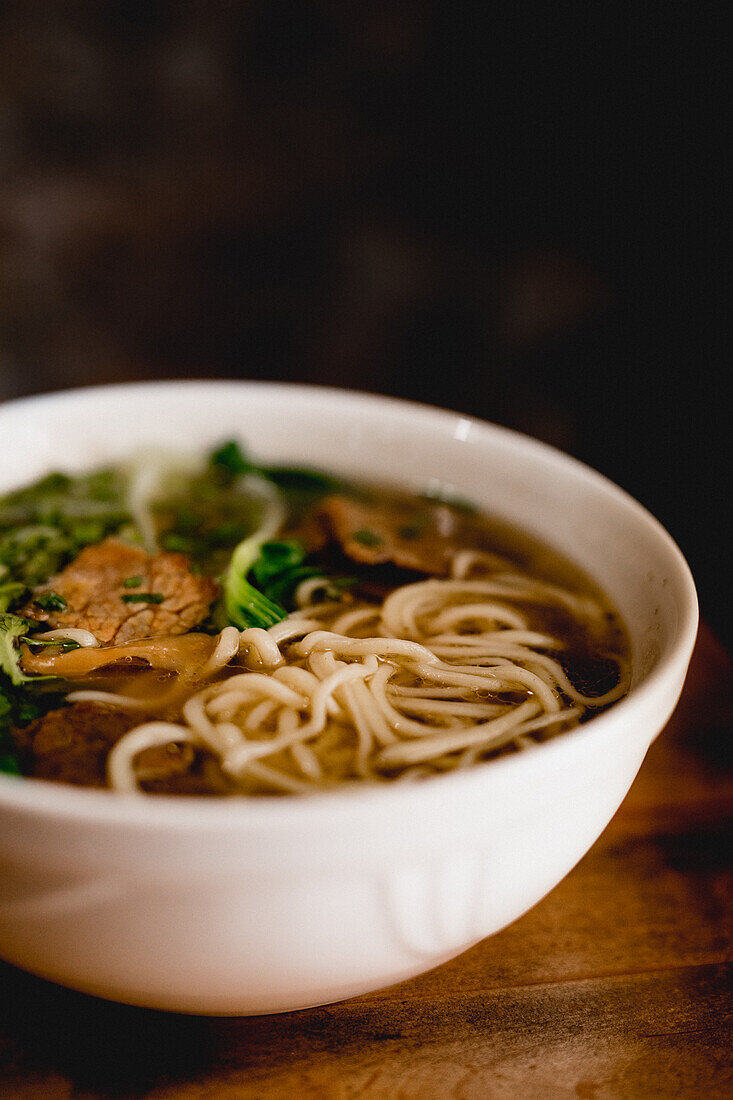 Von oben große weiße Keramikschüssel mit Rindfleisch-Ramen-Suppe