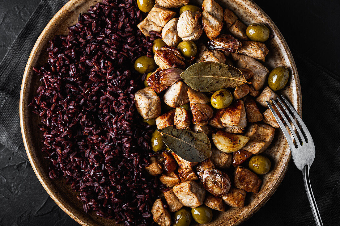 From above close-up of round plate with tasty sauteed turkey with olives