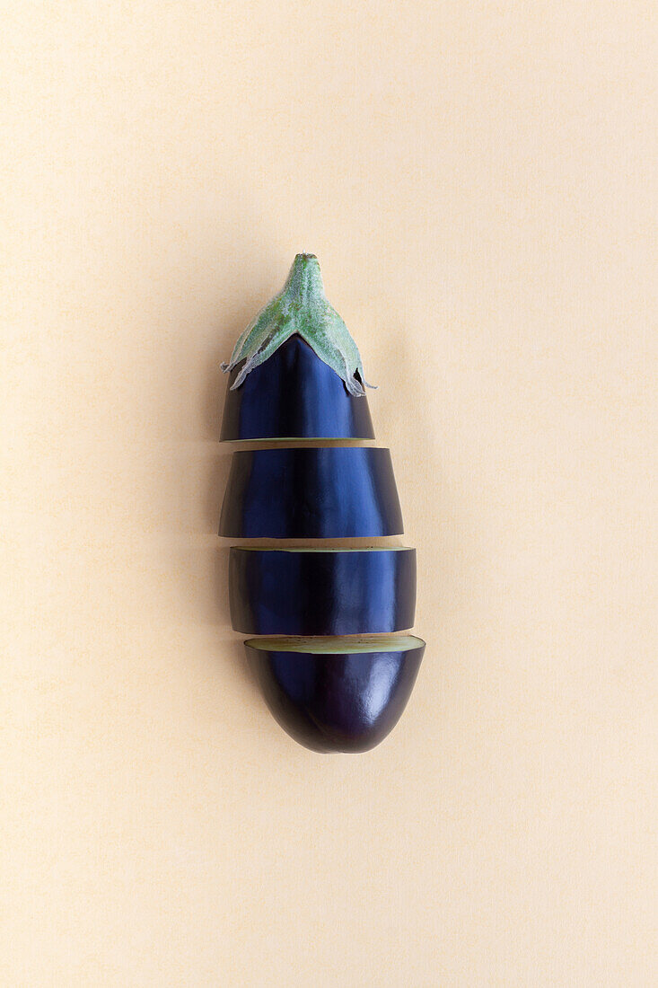 From above of ripe aubergine cut in pieces placed on beige background in studio