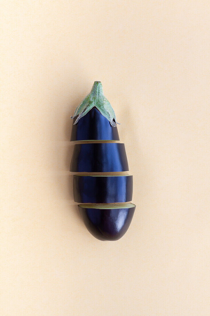 Von oben aufgeschnittene reife Aubergine auf beigem Hintergrund in einem Studio