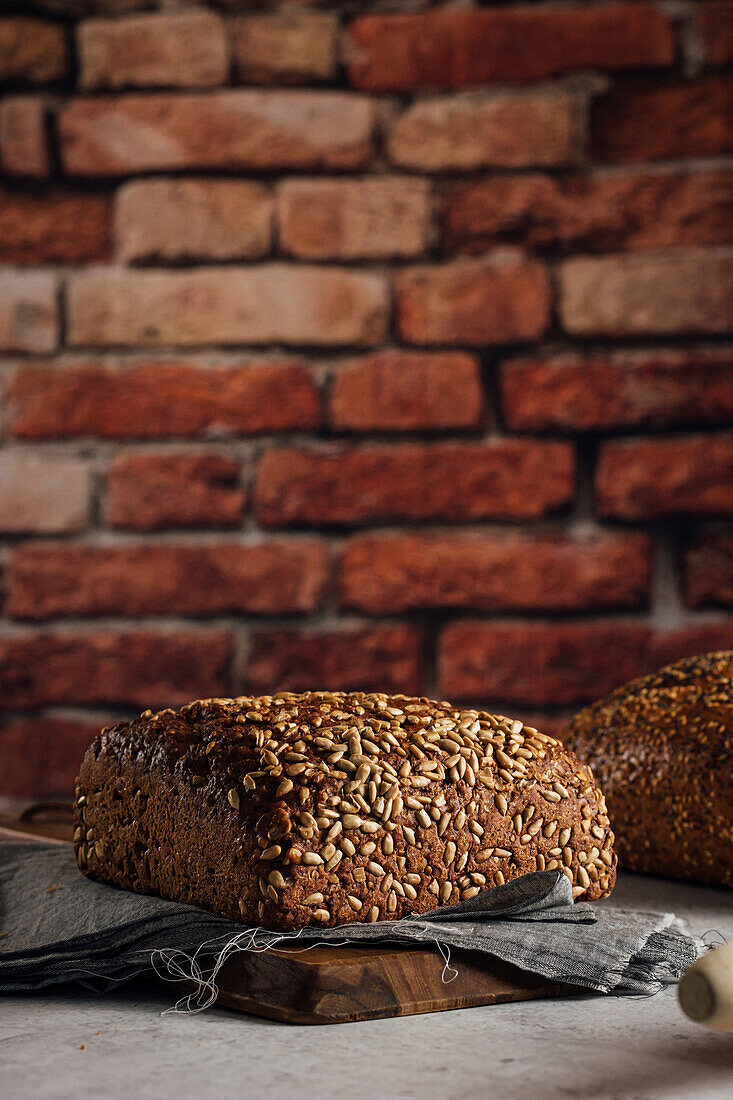 Leckeres Vollkornbrot auf Schneidebrett auf Tisch