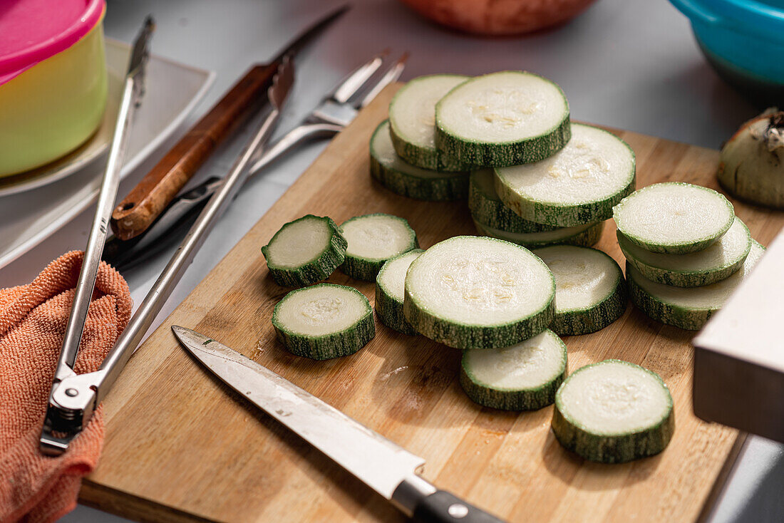 Von oben aufgeschnittene Stücke frischer reifer Zucchini, die mit einem Messer auf ein Holzbrett gelegt werden