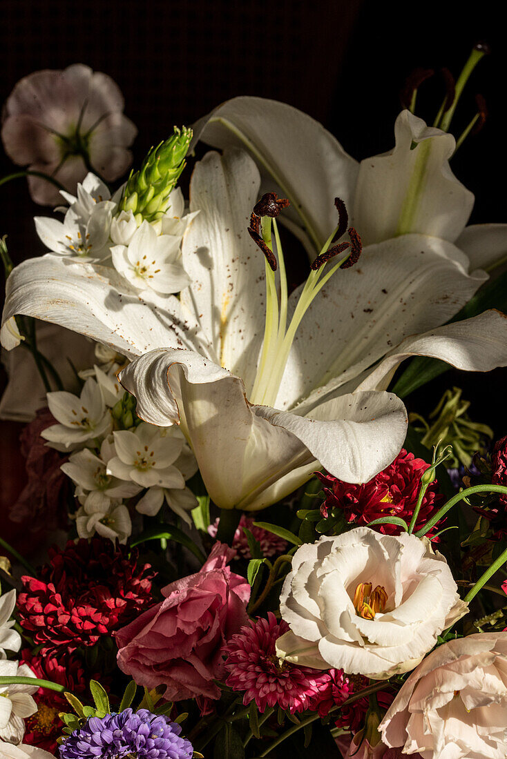Bouquet of fresh flowers including white lilies eustoma and aster in glass vase at sunshine