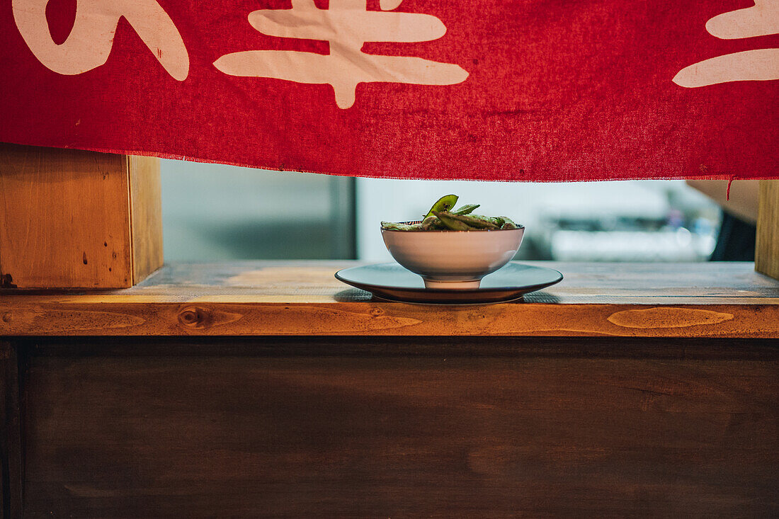 Traditionelles asiatisches Gericht in weißer Keramikschale am Holzfenster eines Restaurants