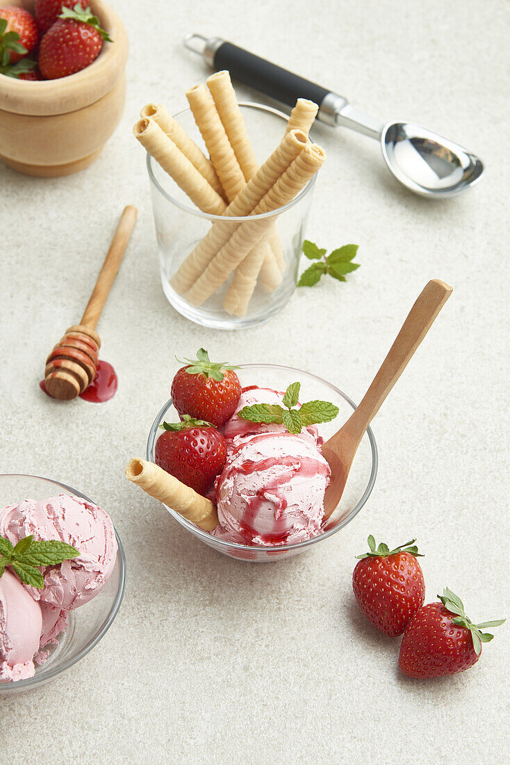 Hoher Blickwinkel auf köstliches hausgemachtes Erdbeereis in einer Glasschale mit Beeren und Waffelrolle in der Küche bei Tageslicht