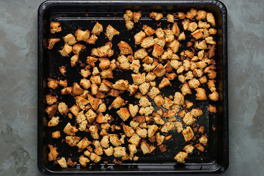 Top view cubes of baked bread served on black tray after baking on marble table in home kitchen