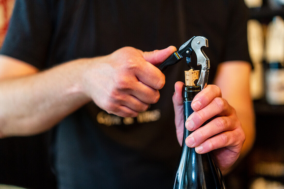 Erntehelfer öffnet Glasflasche mit Wein auf dem Tresen