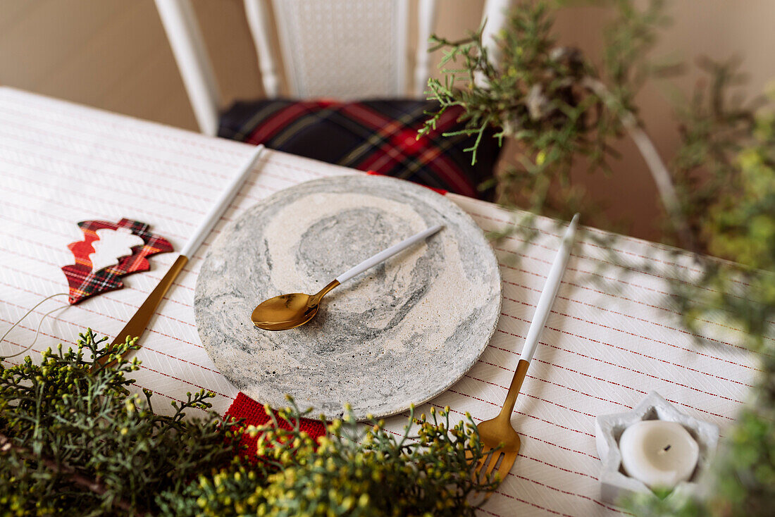 Von oben auf einen weihnachtlich gedeckten Tisch mit Kranzdekoration, rot und weiß, mit goldenem Besteck und Kerzen