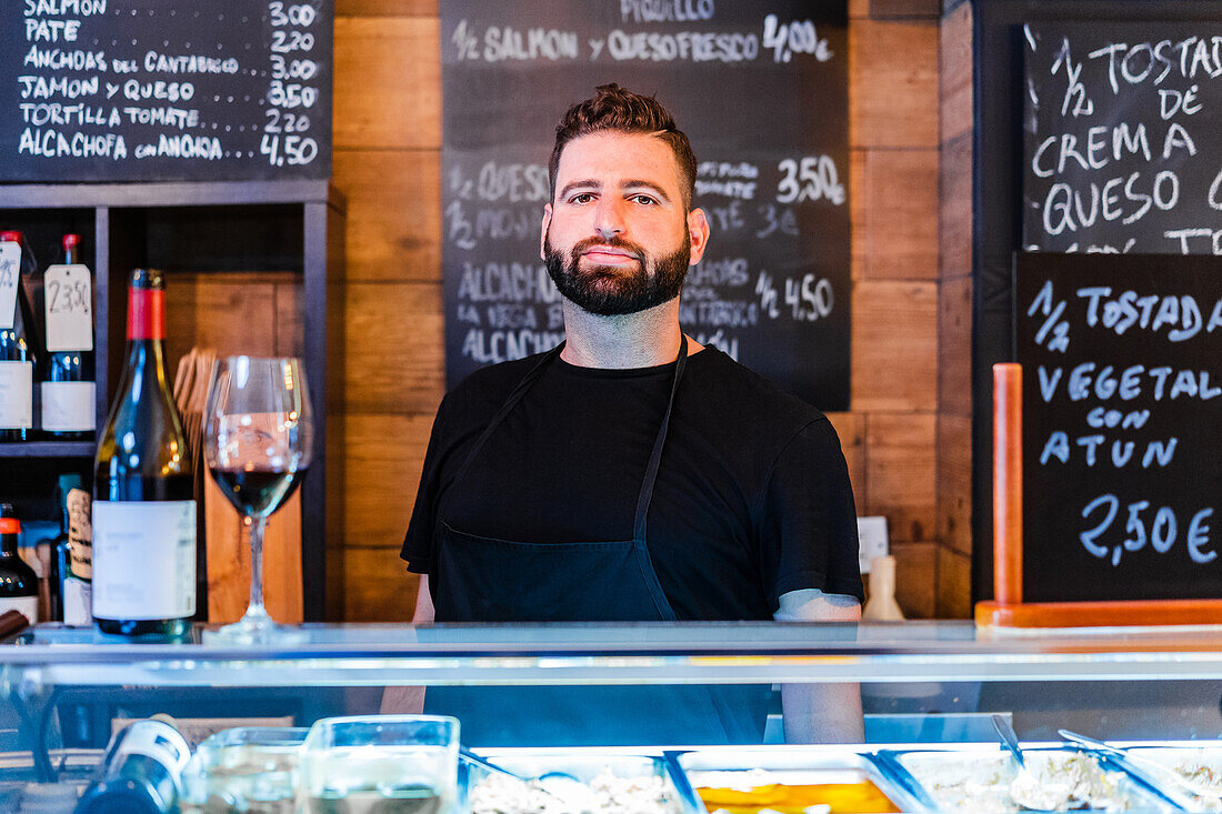 Barkeeper neben Weinflasche auf Tresen in Restaurant mit vielen Schildern