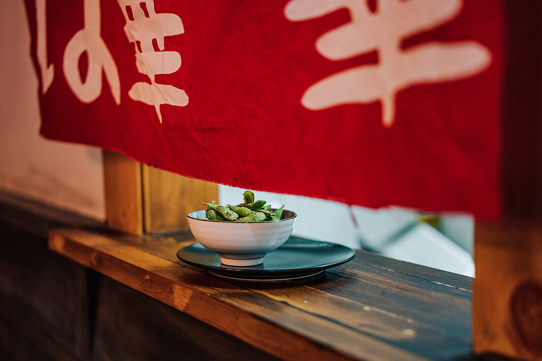 Traditionelles asiatisches Gericht in weißer Keramikschale am Holzfenster eines Restaurants