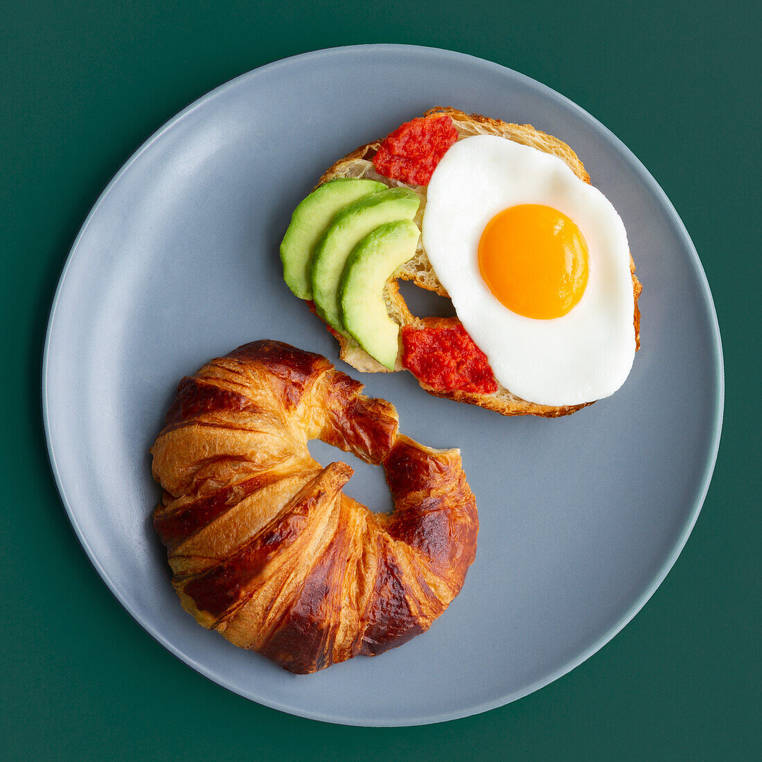 Teller von oben betrachtet mit Croissant und Avocado-Ei-Toast