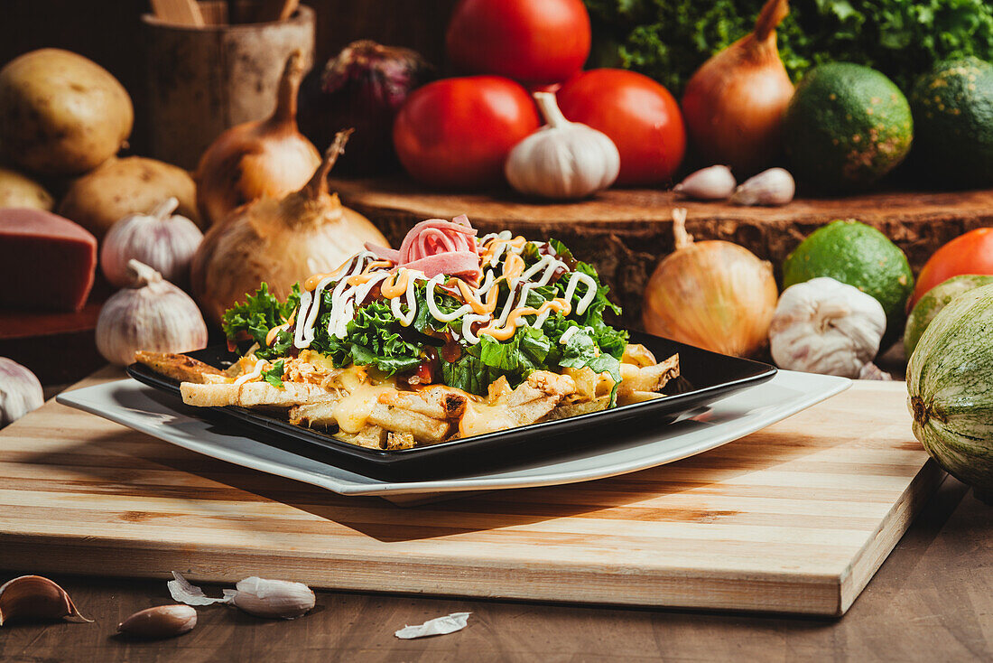 Leckere Pommes frites mit frischem Salat und Schinken unter Soßen auf einem Teller auf dem Tisch