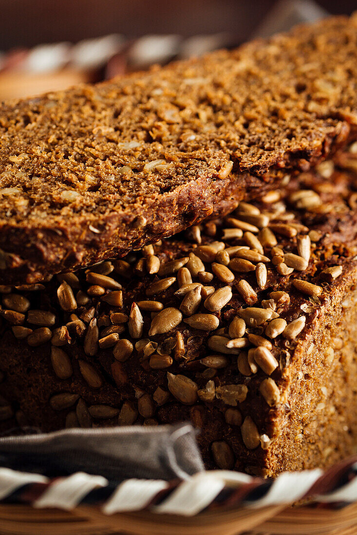 Nahaufnahme von leckerem geschnittenem Brot mit brauner Kruste und knusprigen Sonnenblumenkernen in einem Weidenkorb