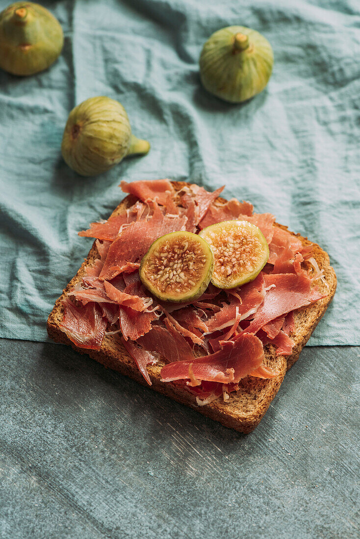 Köstlicher Toast mit Iberico-Schinken, Käse und frischen Feigen auf dem blauen Tischtuch, Köstliche Vorspeise, ideal als Aperitif. Gesundes Essen